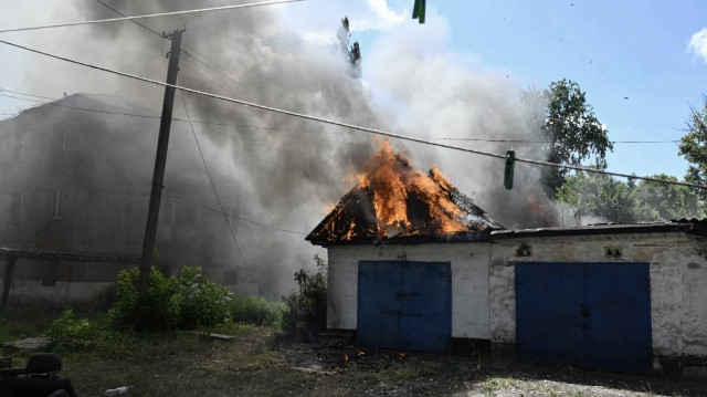 Un garage en feu et un immeuble résidentiel endommagé sont visibles après une frappe de drone russe dans la ville de Bilozerske, dans la région de Donetsk, le 10 août 2025, dans le contexte de l'invasion russe de l'Ukraine.