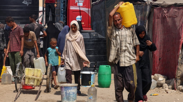 Des Palestiniens déplacés remplissent des conteneurs d'eau dans la région de Mawasi, près de Khan Yunis, le 14 août 2025, alors que les organisations internationales s'efforcent de fournir de l'eau potable à la population dans un contexte de crise qui s'aggrave et de propagation de maladies dues au manque d'hygiène dans la bande de Gaza.