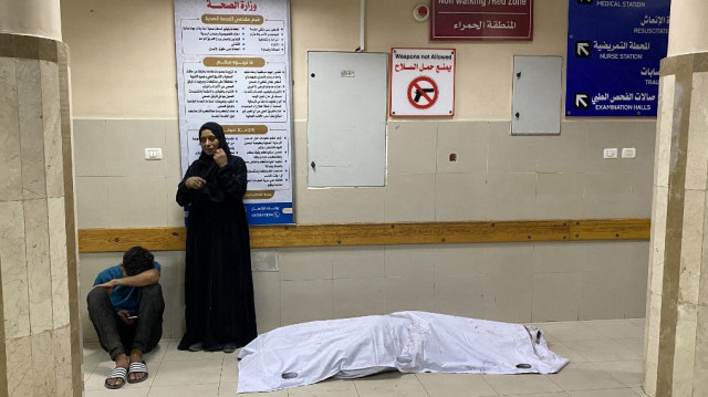 Des Palestiniens se tiennent près d'un corps recouvert d'un drap au complexe médical Nasser à Khan Yunis, dans le sud de la bande de Gaza, le 7 août 2025, à la suite du bombardement israélien de la zone de Mawasi à Khan Yunis.