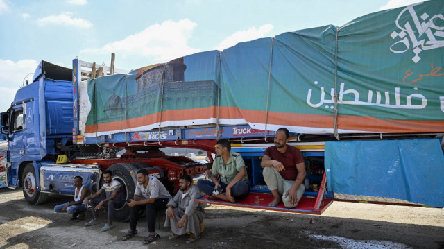 Des chauffeurs attendent à côté d'un camion chargé d'aide humanitaire pour Gaza, du côté égyptien du poste-frontière de Rafah, le 18 août 2025.