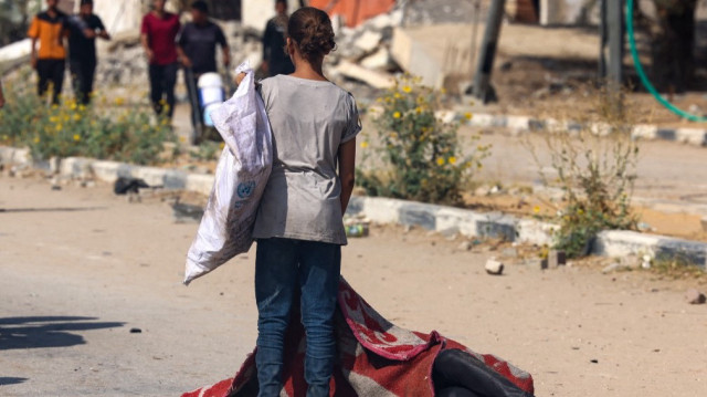 Une fillette palestinienne se tient près du corps recouvert d'un drap d'une personne tuée alors qu'elle cherchait de la nourriture dans un centre de distribution géré par l'organisation Gaza Humanitarian Foundation (GHF), soutenue par les États-Unis et Israël, sur la route Salah al-Din à Nusseirat, dans le centre de la bande de Gaza, le 4 août 2025.