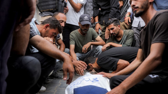 Les personnes en deuil se rassemblent autour du corps du correspondant d'Al Jazeera Mohammed Qreiqeh alors qu'elles se préparent pour ses funérailles à l'hôpital Al-Shifa de Gaza City, le 11 août 2025.