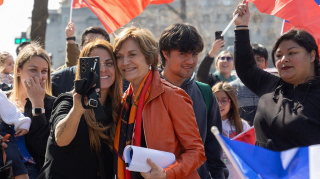 La candidate à la présidence du Chili, Evelyn Matthei (au centre), pose pour un selfie avec un partisan après avoir déposé sa candidature au bureau du Servel à Santiago, le 16 août 2025.