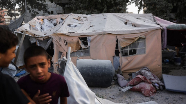 Des jeunes Palestiniens se rassemblent près d'une tente de déplacés endommagée à la suite d'une frappe israélienne sur un immeuble de six étages dans le quartier de Saftawi, à l'ouest de Jabalia, dans le nord de la bande de Gaza, le 19 août 2025.