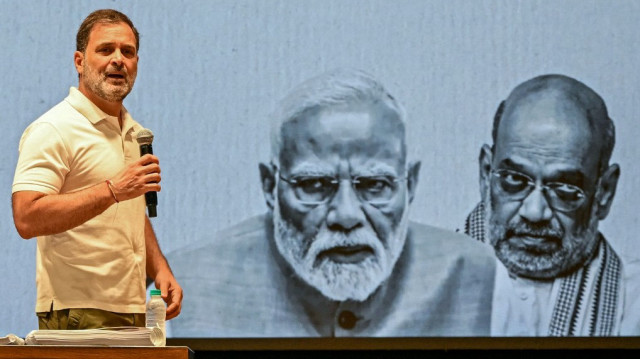 Le chef du parti du Congrès national indien (INC), Rahul Gandhi (à gauche), s'adresse aux médias devant un écran montrant le Premier ministre indien Narendra Modi (au centre) et le ministre de l'Intérieur Amit Shah, au siège du parti à New Delhi, le 7 août 2025, à l'approche des élections législatives dans l'État indien du Bihar.