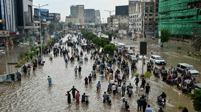 Des personnes pataugent dans une rue inondée après de fortes pluies à Karachi, le 19 août 2025.