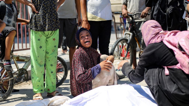 Une femme réagit à côté du corps d'un Palestinien qui a été abattu alors qu'il cherchait de l'aide à un point de distribution de la Fondation humanitaire de Gaza, soutenue par les États-Unis, à l'entrée du camp de réfugiés de Bureij, dans le centre de la bande de Gaza, le 27 juillet 2025.