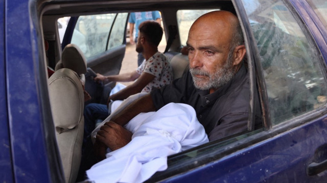 Un Palestinien porte le corps recouvert d'un linceul d'un proche, tué lors d'une frappe israélienne, avant ses funérailles à l'hôpital Al-Shifa de Gaza, le 21 août 2025.