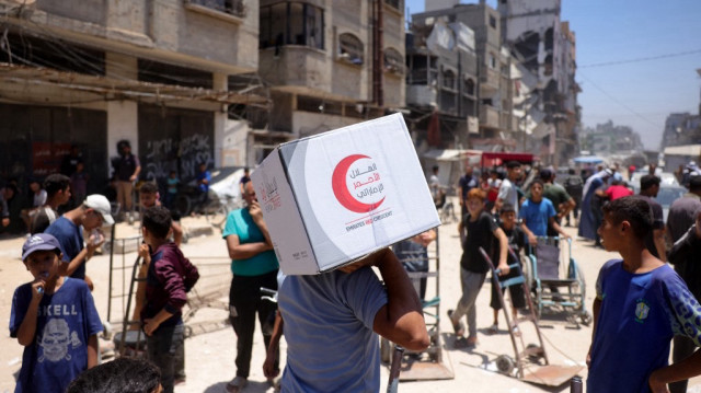 Un Palestinien emporte un colis alimentaire offert par le Croissant-Rouge des Émirats arabes unis, depuis un point de distribution supervisé par des bénévoles issus de familles palestiniennes organisées en comités afin de prévenir les vols, à Gaza, le 26 juin 2025.