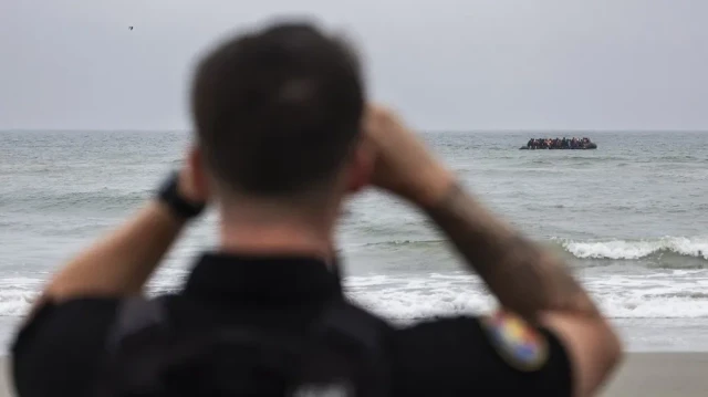 Des gendarmes français observent des migrants à bord d'un bateau de passeurs alors qu'ils tentent de traverser la Manche au large de la plage d'Hardelot, à Neufchâtel-Hardelot, dans le nord de la France, le 13 août 2025.