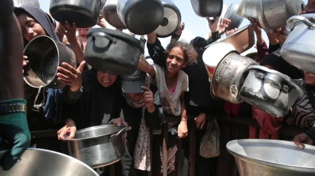 Des femmes et des enfants palestiniens tendent leurs casseroles vides devant une cuisine communautaire à Khan Yunis, dans le sud de la bande de Gaza, le 21 août 2025.