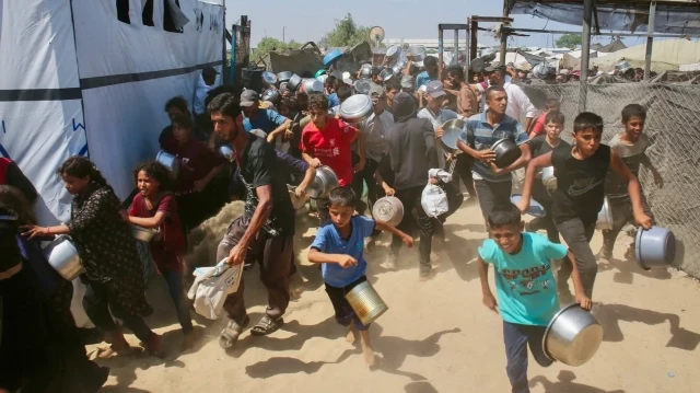 Les Palestiniens se précipitent pour faire la queue devant une cantine sociale dans le quartier de Mawasi, à Khan Yunis, dans le sud de la bande de Gaza, le 22 juillet 2025.