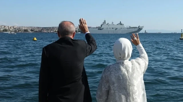 Turkish President Recep Tayyip Erdogan (L) greets the ships of the Turkish Navy passing through the Bosphorus Strait, which included TCG Savarona, TCG Anadolu, and seven other ships, from the Dolmabahce Working Office during TEKNOFEST 'Blue Homeland' event in Istanbul, Turkiye on August 24, 2025. President Erdogan was accompanied by his wife, Emine Erdoğan, during the greeting.