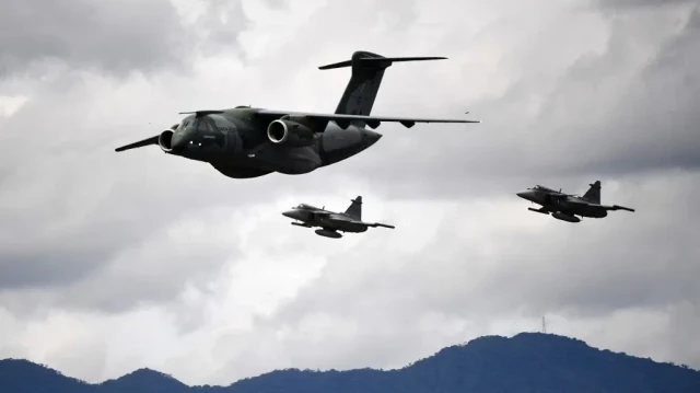 Un pilote de l'armée de l'air brésilienne aux commandes de son avion Embraer C-390 Millennium, escorté par deux chasseurs Saab JAS 39 Gripen, effectue une démonstration lors du salon aéronautique F-Air Colombia 2025 à Rionegro, dans le département d'Antioquia, en Colombie, le 11 juillet 2025.