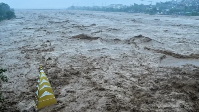 Un torrent d'eau s'abat sur un temple hindou partiellement submergé par les inondations après que de fortes pluies ont provoqué une montée du niveau de la rivière Tawi à Jammu, le 26 août 2025.