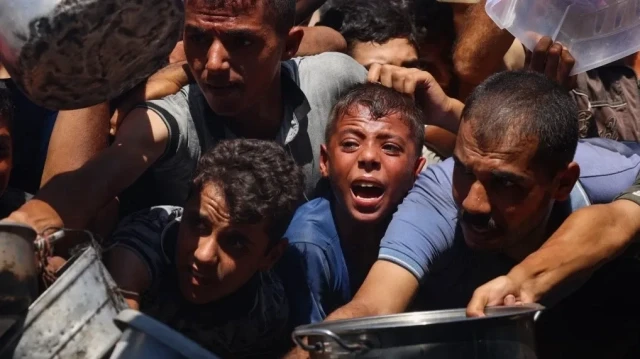 Des Palestiniens se bousculent pour recevoir des portions de nourriture dans une cuisine caritative à Khan Younes, dans le sud de la bande de Gaza, le 27 août 2025.