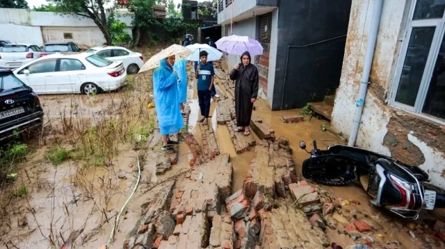 Des hommes de la région examinent un scooter endommagé dans un quartier résidentiel recouvert de boue après que de fortes pluies ont provoqué des crues soudaines à Jammu, en Inde, le 27 août 2025.