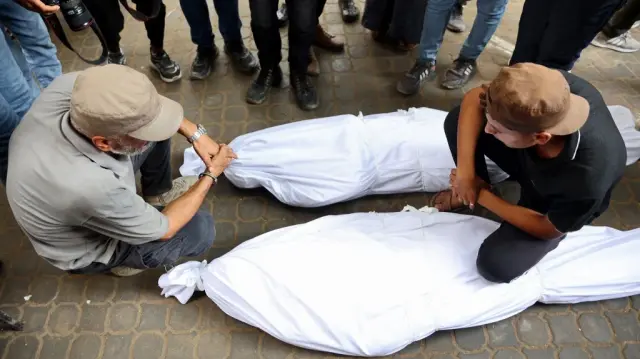 Des Palestiniens pleurent la mort de leurs proches tués la veille alors qu'ils cherchaient de l'aide près de Zikim, à l'ouest de Beit Lahia, dans le nord de la bande de Gaza, à l'hôpital Al-Shifa de Gaza City, le 10 août 2025.