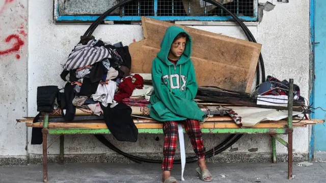 Une fillette palestinienne observe d'autres personnes déblayer les décombres d'un camp de tentes de fortune pour déplacés, touché la veille par des frappes israéliennes, à l'école pour filles Abou Helou gérée par l'UNRWA dans le camp de réfugiés de Bureij, dans le centre de la bande de Gaza, le 17 juillet 2025.