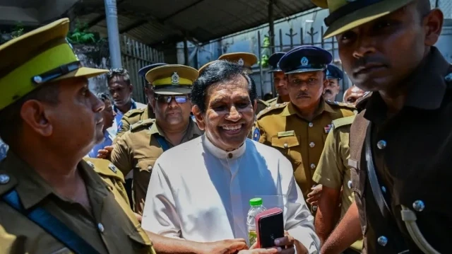 Des agents de sécurité escortent l'ancien ministre sri-lankais de la Pêche, Rajitha Senaratne (au centre), à la sortie d'un tribunal de Colombo, le 29 août 2025.
