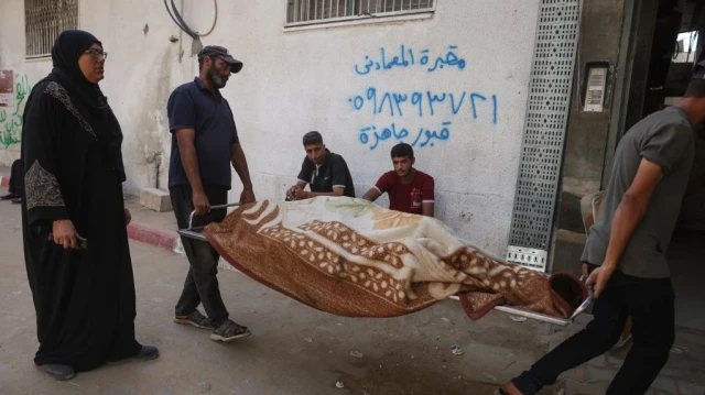 Des Palestiniens transportent un corps enveloppé dans une couverture à l'extérieur de l'hôpital Shifa de Gaza, où les victimes des tirs israéliens ont été transportées avant leurs funérailles, le 29 août 2025, alors que la guerre entre Israël et le mouvement militant Hamas se poursuit. 