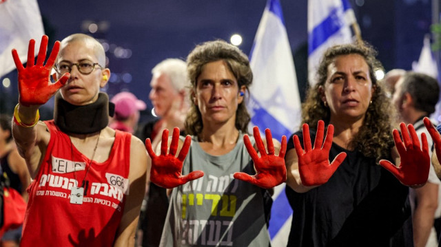 Des manifestants montrent leurs mains peintes en rouge pour représenter le sang lors d'une manifestation anti-gouvernementale appelant à une action pour obtenir la libération des otages israéliens détenus dans la bande de Gaza, devant le siège du ministère israélien de la Défense à Tel-Aviv, le 2 août 2025.