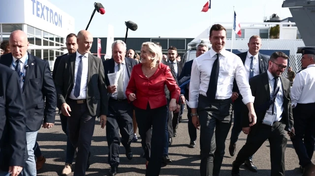 La présidente du groupe parlementaire du Rassemblement national, Marine Le Pen (C en rouge), et le président du parti d'extrême droite français Rassemblement national (RN), Jordan Bardella (au centre à droite), visitent la 55e édition du Salon international de l'aéronautique et de l'espace - SIAE) à l'aéroport Paris-Le Bourget, au Bourget, au nord de Paris, le 19 juin 2025.