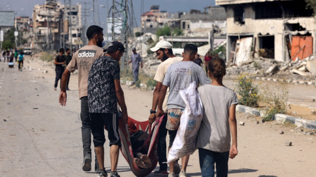 Une fillette palestinienne regarde des personnes transporter le corps d'une personne tuée alors qu'elle cherchait de la nourriture dans un centre de distribution géré par l'organisation Gaza Humanitarian Foundation (GHF), soutenue par les États-Unis et Israël, sur la route Salah al-Din à Nusseirat, dans le centre de la bande de Gaza, le 4 août 2025.