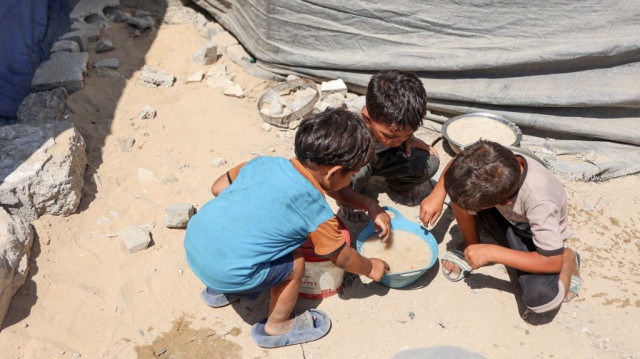 Des enfants palestiniens partagent un bol de soupe aux lentilles obtenu dans un centre de distribution alimentaire à Gaza, le 1er août 2025.