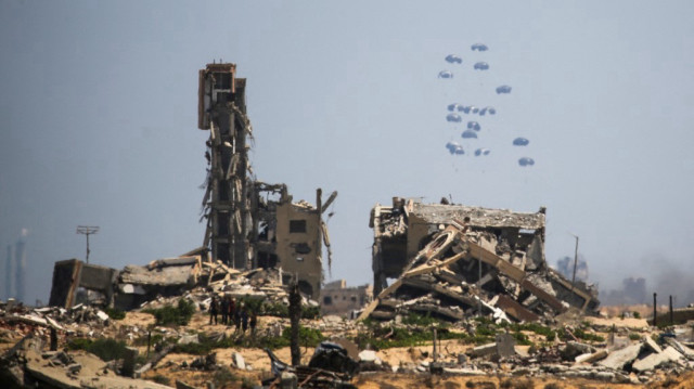 Des Palestiniens regardent des colis d'aide humanitaire parachutés dans la région de Nuseirat, dans le centre de la bande de Gaza, lors d'un largage aérien au-dessus du territoire palestinien assiégé par Israël, le 6 août 2025.