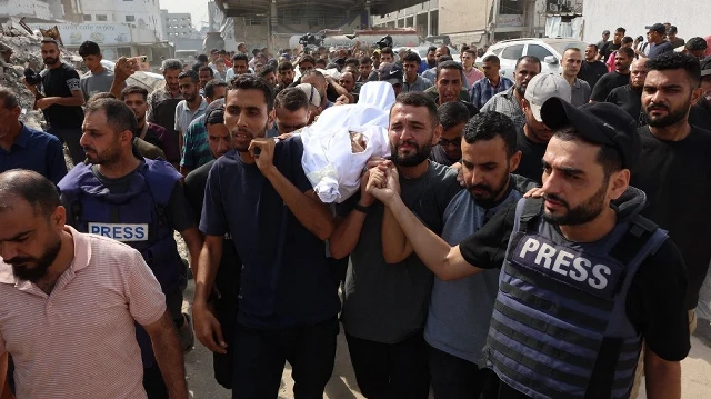 Des personnes en deuil transportent le corps d'un Palestinien, tué lors d'une frappe israélienne nocturne, avant des funérailles collectives devant l'hôpital Al-Shifa à Gaza, le 11 août 2025.