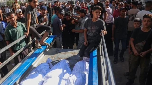 Des Palestiniens sont assis près des corps recouverts d'un linceul des victimes des frappes israéliennes sur la ville de Gaza la nuit précédente, alors qu'ils sont transportés pour être enterrés depuis l'hôpital Al-Shifa, le 1er septembre 2025.