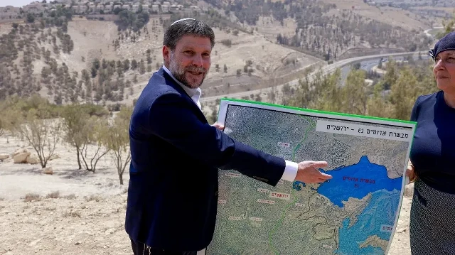 Le ministre israélien des Finances d'extrême droite, Bezalel Smotrich, montre une carte d'une zone proche de la colonie de Maale Adumim, un corridor terrestre connu sous le nom de E1, à l'extérieur de Jérusalem, en Cisjordanie occupée, le 14 août 2025, après une conférence de presse sur place.