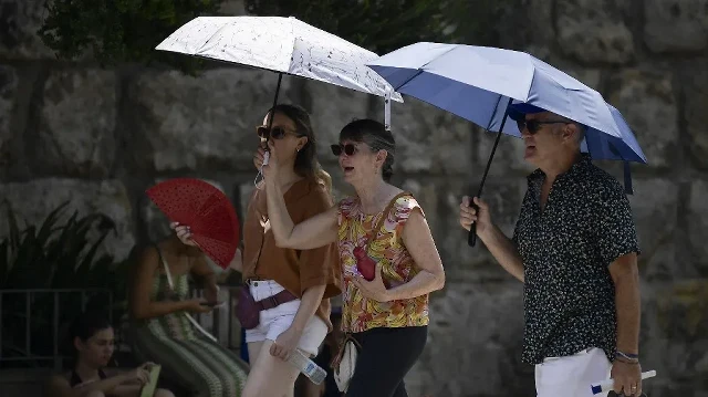 Les gens se protègent du soleil avec un parapluie pendant la vague de chaleur extrême qui frappe Séville, où les températures dépassent les quarante degrés, le 12 août 2025. Selon l'agence météorologique nationale, les températures enregistrées en Espagne en août 2025 ont égalé le record de l'année dernière, rapporte l'AFP le 5 septembre 2025.