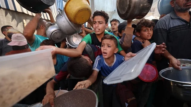 Des Palestiniens font la queue pour recevoir un repas chaud distribué par une cuisine caritative dans le camp de réfugiés de Nuseirat, dans la bande de Gaza assiégée par Israël, le 11 septembre 2025, alors que l'ONU a déclaré une famine après près de deux ans de guerre.