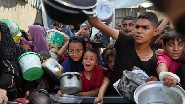 Des Palestiniens font la queue pour recevoir un repas chaud distribué par une cuisine caritative dans le camp de réfugiés de Nuseirat, dans la bande de Gaza assiégée par Israël, le 11 septembre 2025, alors que l'ONU a déclaré une famine après près de deux ans de guerre.