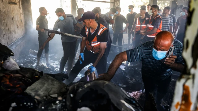Les premiers intervenants de la défense civile palestinienne et d'autres personnes inspectent les restes d'une salle de classe incendiée après avoir éteint un incendie suite à une frappe israélienne contre l'école Osama bin Zaid de l'UNRWA dans le district de Saftawi, à l'ouest de Jabalia, dans le nord de la bande de Gaza, le 27 juin 2025.
