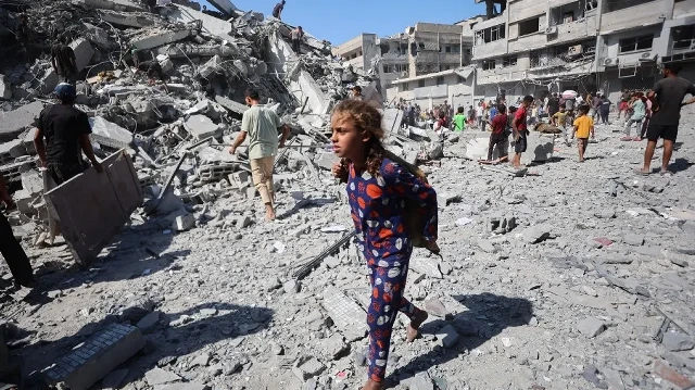 Des Palestiniens déplacés récupèrent des objets dans les décombres de la tour al-Ghafari après sa destruction lors de frappes israéliennes à Gaza le 15 septembre 2025.
