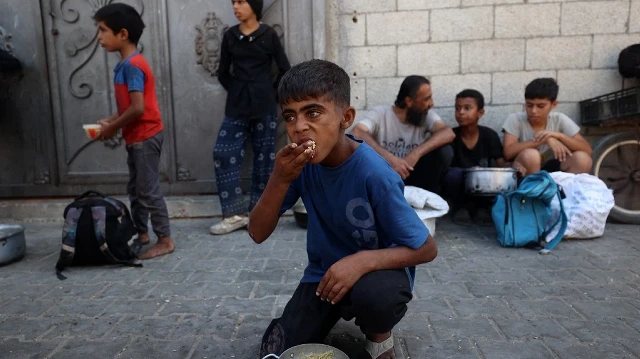 Un enfant palestinien mange du riz dans une marmite, devant une cuisine communautaire dans le camp de réfugiés de Nuseirat, dans le centre de la bande de Gaza, le 14 septembre 2025, alors que l'ONU a déclaré une famine après près de deux ans de guerre.