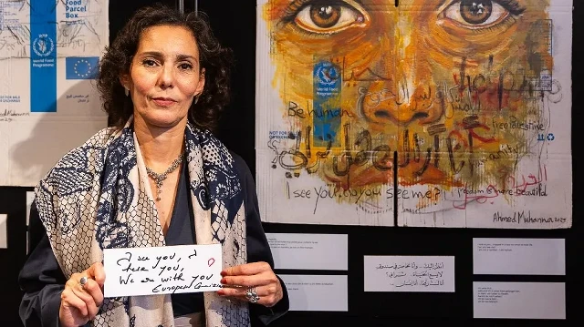 La commissaire européenne chargée de l'égalité, de la préparation et de la gestion des crises, Hadja Lahbib, tient une pancarte sur laquelle on peut lire "Je vous vois, je vous entends. Nous sommes avec vous" après avoir donné une conférence de presse lors de l'exposition itinérante de l'artiste palestinien Ahmed Muhanna "Gaza : histoires d'espoir et de résilience", organisée par la Commission européenne et le Programme alimentaire mondial des Nations unies, à Bruxelles, le 17 septembre 2025.