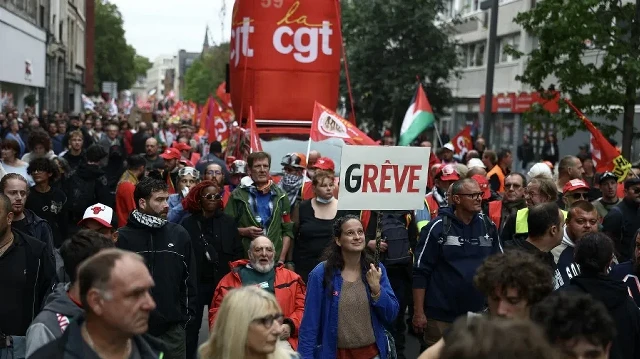 Une femme brandit une pancarte sur laquelle on peut lire "Grève" alors qu'elle participe à une manifestation aux côtés de manifestants brandissant des drapeaux du syndicat français CGT à Lille, dans le nord de la France, le 18 septembre 2025, lors d'une journée de grève et de manifestations nationales organisées par les syndicats pour protester contre le budget national français.