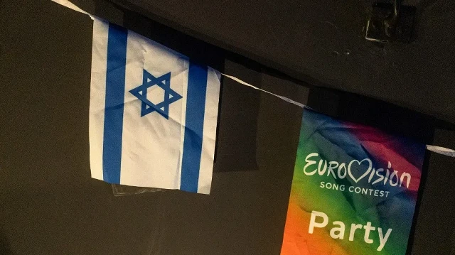 Un drapeau israélien est accroché à côté d'un drapeau de l'Eurovision lors d'une projection de la finale du Concours Eurovision de la chanson 2025 dans un centre communautaire à Tel Aviv, en Israël, le 17 mai 2025. 