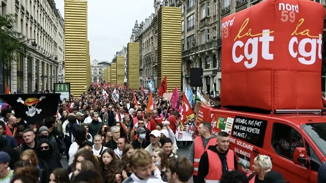 Une structure gonflable arborant le logo du syndicat français CGT passe devant l'œuvre de l'artiste urbain espagnol SpY intitulée "Golden Monoliths" à Lille, dans le nord de la France, le 18 septembre 2025, lors d'une journée de grèves et de manifestations nationales organisées par les syndicats pour protester contre le budget national français. 