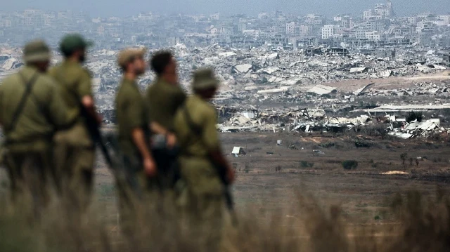 Des soldats de l'armée israélienne regardent les bâtiments détruits dans la bande de Gaza alors qu'ils se tiennent à la frontière avec le territoire palestinien, le 13 août 2025, alors que la guerre entre Israël et le groupe militant palestinien Hamas se poursuit.