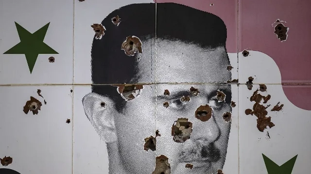 Des impacts de balles défigurent une peinture murale représentant le président syrien déchu Bachar al-Assad dans la ville d'Adra, à la périphérie nord-est de Damas, le 25 décembre 2024.