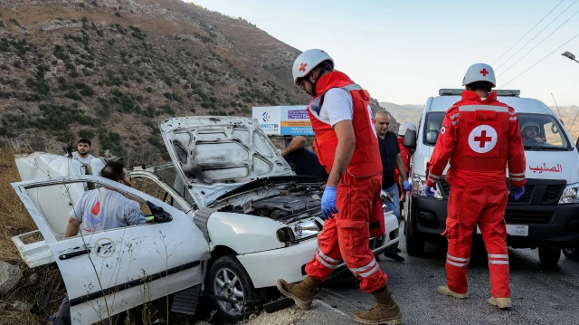 Les premiers intervenants et les membres des forces de sécurité se rassemblent sur le site d'une frappe israélienne contre un véhicule sur la route de Khardali, dans la région de Marjayoun, au sud du Liban, le 20 septembre 2025.