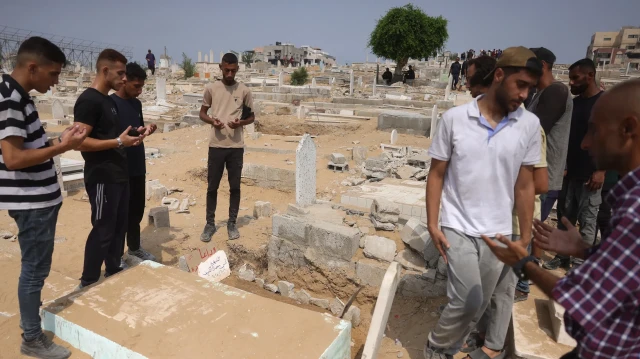 Des Palestiniens récitent la Fatiha sur la tombe du correspondant d'Al Jazeera Anas al-Sharif, tué avec d'autres journalistes lors d'une frappe israélienne, dans un cimetière de la ville de Gaza, le 12 août 2025.