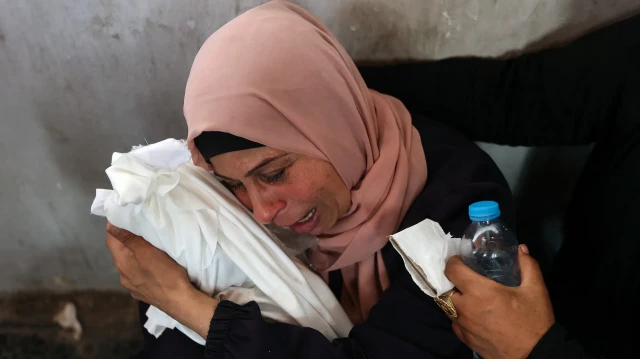 Une Palestinienne pleure en tenant dans ses bras le corps recouvert d'un linceul d'un bébé tué lors d'une frappe israélienne dans le quartier de Shujaiyya à Gaza, à l'hôpital Ahli Arab, également connu sous le nom d'hôpital Maamadani (baptiste), à Gaza, le 9 avril 2025.