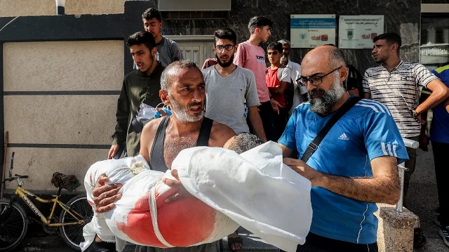 Un homme réagit alors qu'il transporte le corps d'un enfant tué par un bombardement israélien présumé sur al-Bureij, à l'extérieur de l'hôpital al-Awda à Nuseirat, dans le centre de la bande de Gaza, le 21 septembre 2025.