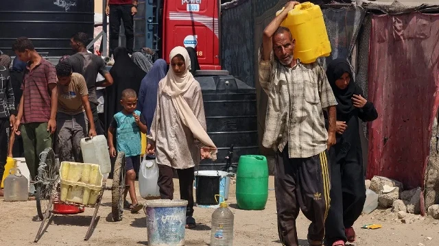 Des Palestiniens déplacés remplissent des conteneurs d'eau dans la région de Mawasi, à Khan Yunis, le 14 août 2025, alors que les organisations internationales s'efforcent de fournir de l'eau potable à la population dans un contexte de crise qui s'aggrave et de propagation de maladies dues au manque d'hygiène dans la bande de Gaza.